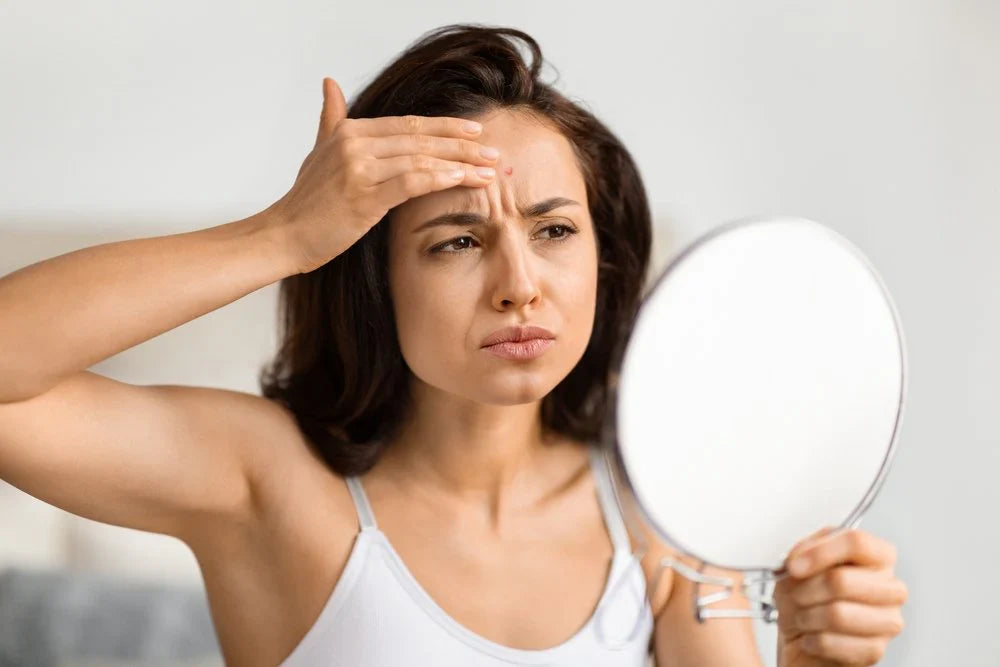 woman noticing forehead wrinkles in mirror skincare concern